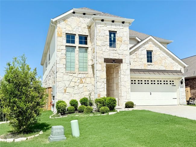 Modern meets French country home with stone siding, driveway, a front yard, a shingled roof, and an attached garage | Image 40