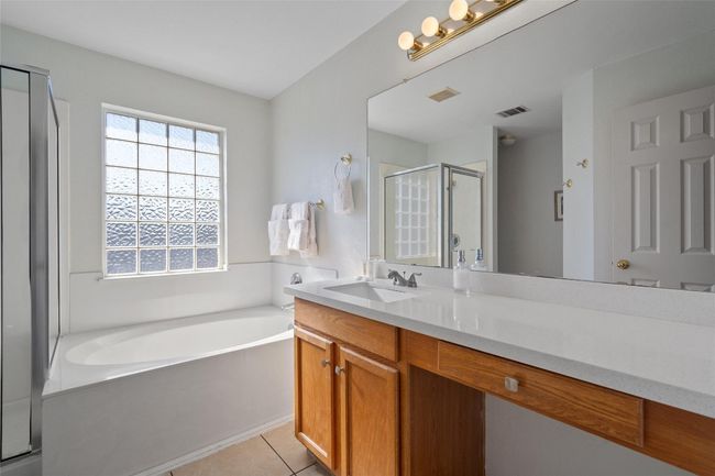 Bathroom featuring a stall shower, visible vents, tile patterned floors, a garden tub, and vanity | Image 23