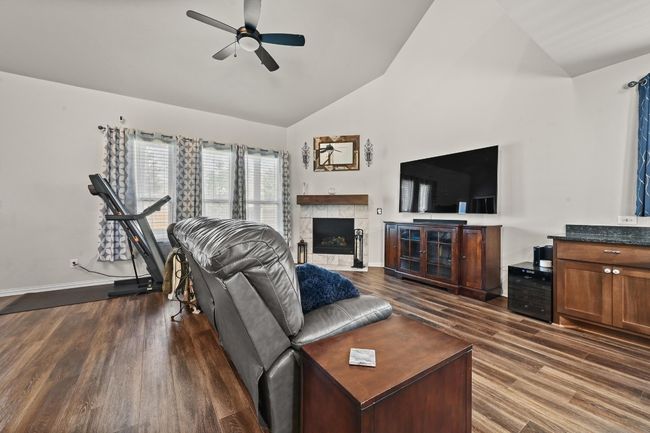 Living area featuring dark wood-style floors, a ceiling fan, a fireplace, and high vaulted ceiling | Image 10