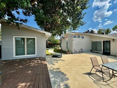 Wooden deck featuring a large concrete patio between main house and guest house | Image 2