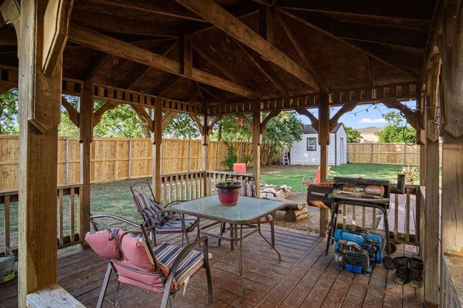 Deck with a fenced backyard, a shed, outdoor dining area, and grilling area | Image 4