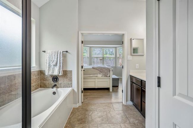 From the walk-in closet, take in the calming view back across the bathroom and through the open double doors to the inviting primary bedroom — a seamless flow that ties this private retreat together beautifully. | Image 23