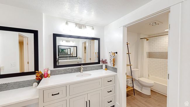 Bathroom featuring vanity, wood finish floors, toilet, a textured ceiling, and shower / bath combo | Image 30