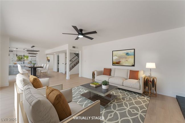 Living area with light wood-type flooring, ceiling fan, and stairs | Image 8