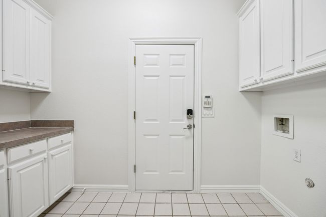Laundry area featuring cabinet space, baseboards, hookup for a washing machine, and light tile patterned floors | Image 25