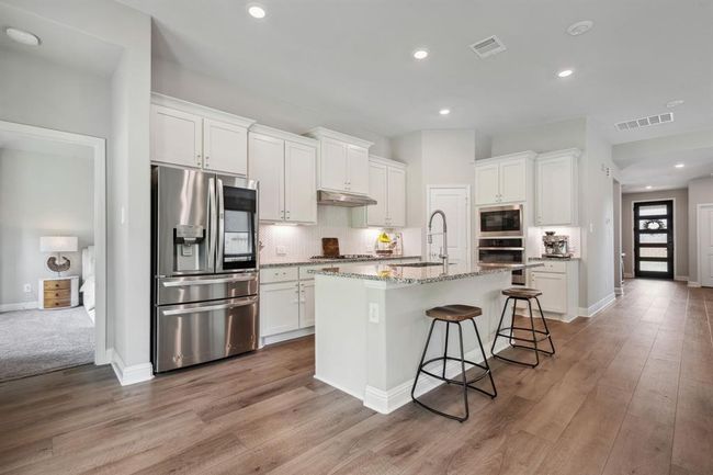 Bright white kitchen with island bar seating | Image 4