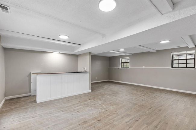 Below grade area with indoor bar, baseboards, a textured ceiling, visible vents, and wood finished floors | Image 26