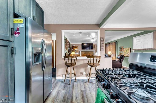 Kitchen featuring appliances with stainless steel finishes, light wood-type flooring, baseboards, a ceiling fan, and a textured ceiling | Image 16