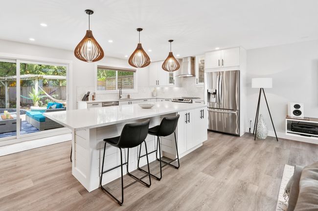 Kitchen featuring a kitchen island, light wood-style floors, wall chimney exhaust hood, stainless steel appliances, and a sink | Image 14