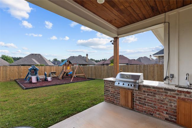 View of yard with an outdoor kitchen, a fenced backyard, a playground, a sink, and a patio | Image 27