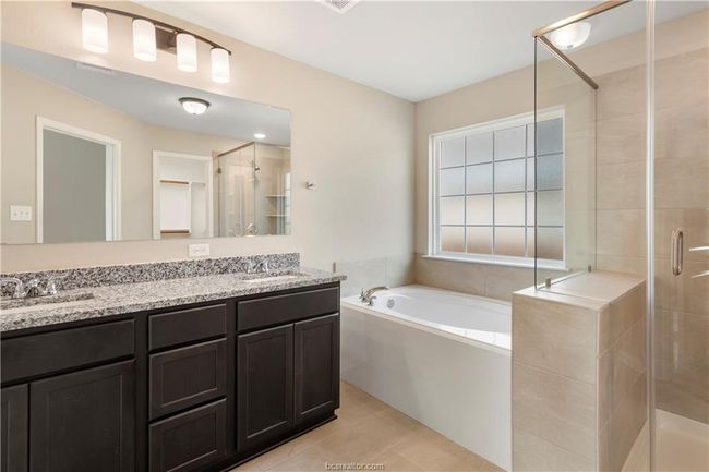 Bathroom featuring a stall shower, a bath, double vanity, and tile patterned flooring | Image 12