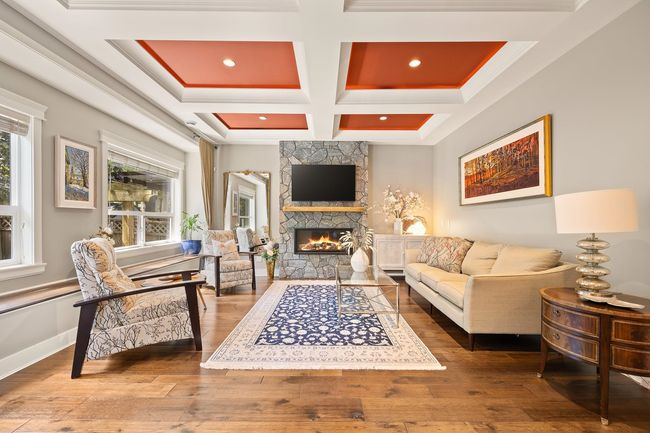 Living room featuring coffered ceiling, a stone fireplace, hardwood / wood-style floors, beam ceiling, and recessed lighting | Image 4