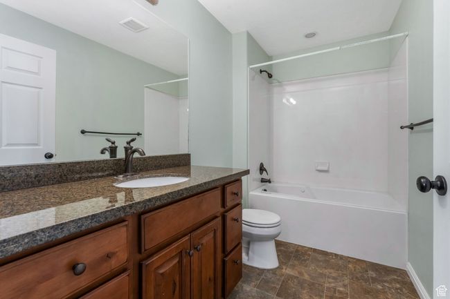 Bathroom with visible vents, stone finish flooring, bathtub / shower combination, toilet, and vanity | Image 15