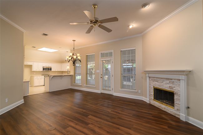 living room with ornamental molding, a fireplace, dark wood-style floors, a chandelier, and ceiling fan | Image 5