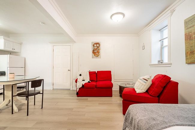 Bedroom with freestanding refrigerator, ornamental molding, and light wood finished floors | Image 25