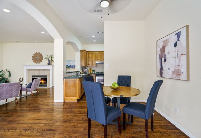 Dining room featuring wood flooring, arched walkways, a ceiling fan, and a tile fireplace | Image 7