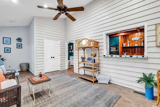 Sitting room with a ceiling fan, wood walls, and wood finished floors | Image 14
