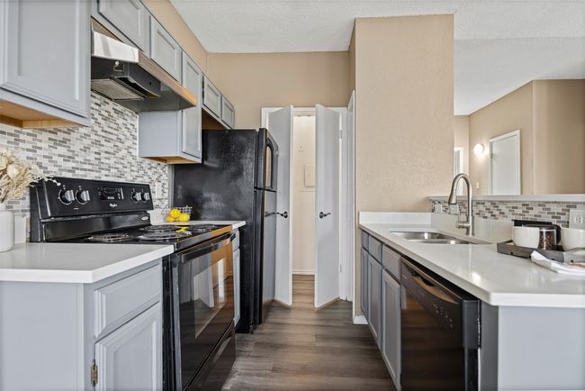 Kitchen featuring sink, dark wood-type flooring, gray cabinetry, black appliances, and a textured ceiling | Image 5