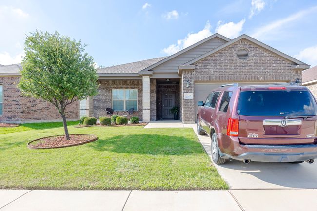 View of front of home with brick siding, an attached garage, a front lawn, and concrete driveway | Image 7