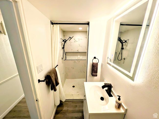 Bathroom with a tile shower, wood finished floors, vanity, and recessed lighting | Image 5
