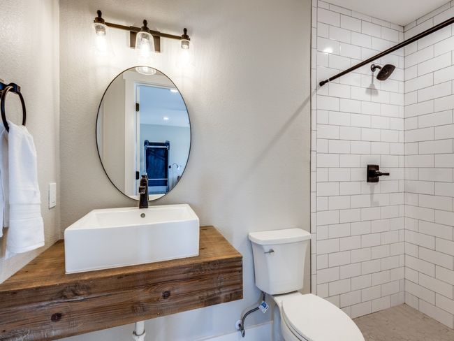 Second living area guest bath is beautifully updated with a stunning vessel sink and wood countertop, and oversized walk-in shower. | Image 26