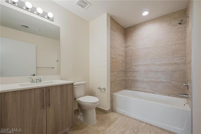 Full bathroom with bathing tub / shower combination, visible vents, vanity, and toilet | Image 10