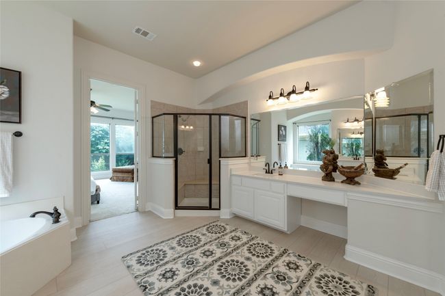 Full bathroom featuring connected bathroom, a stall shower, vanity, a bath, and ceiling fan | Image 20