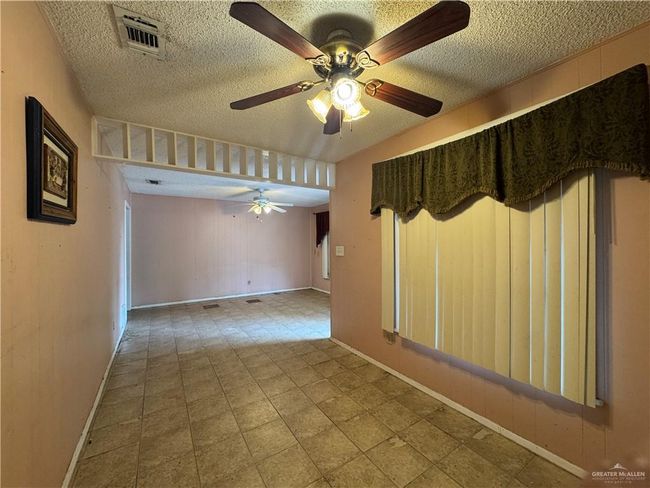 Unfurnished room with a textured ceiling, ceiling fan, and baseboards | Image 12