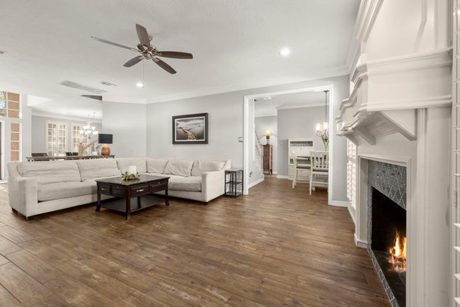 Family room is light and bright with recent floors, fireplace tiles, fresh paint, crisp white moldings, ceiling fan and recessed lighting | Image 11