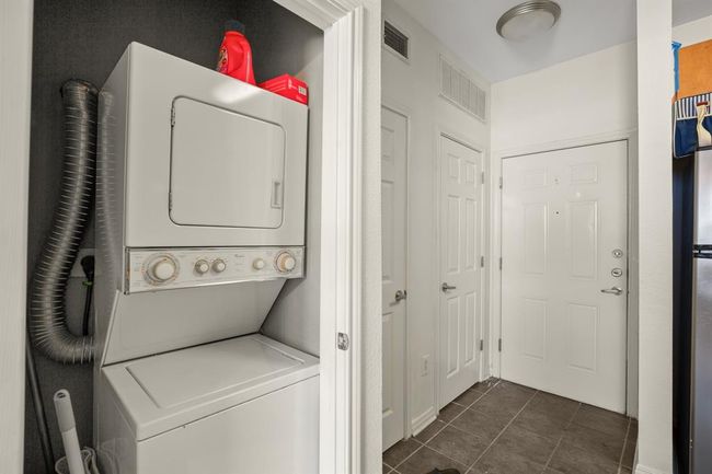 Laundry room with stacked washer and clothes dryer and dark tile patterned floors | Image 12
