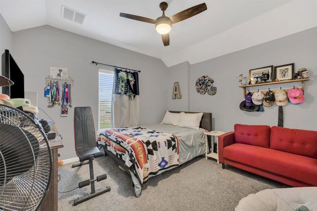 Carpeted bedroom with visible vents, lofted ceiling, baseboards, and ceiling fan | Image 26