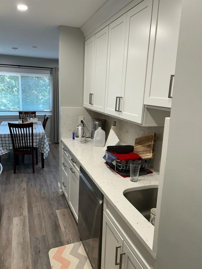 Kitchen featuring stainless steel dishwasher, dark wood finished floors, light stone counters, white cabinetry, and recessed lighting | Image 8
