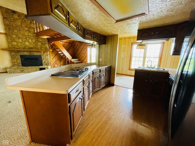 kitchen featuring a sink, electric stovetop, a peninsula, light countertops, and light wood finished floors | Image 6