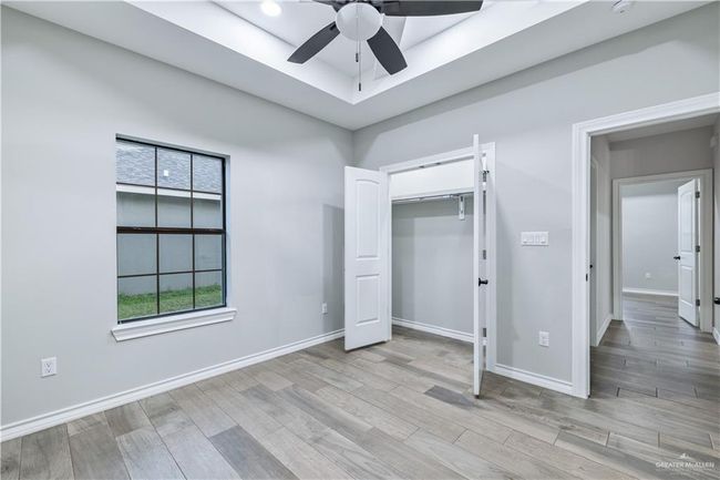Unfurnished bedroom with wood finished floors, ceiling fan, and a closet | Image 9