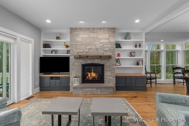 Inviting living area with cozy stone fireplace, custom built in cabinetry, shelving and easy access to front porch. | Image 7