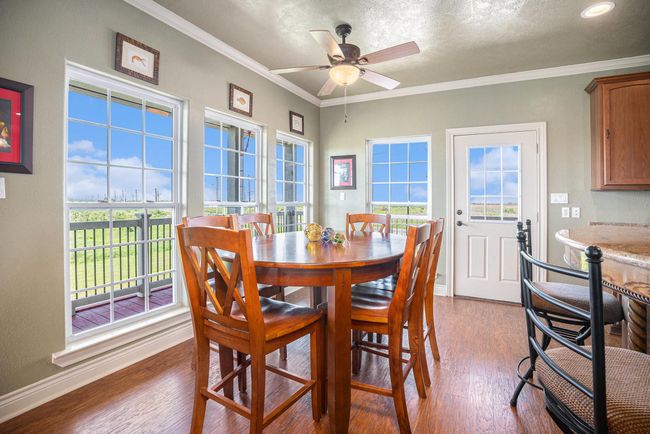 This bright and airy dining area offers a warm and inviting atmosphere. Key features include hardwood flooring, large windows that provide ample natural light and views of the outdoors. | Image 8