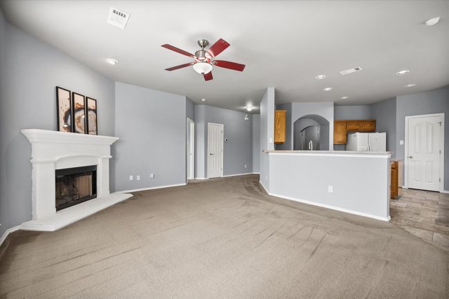 Unfurnished living room featuring a ceiling fan, light colored carpet, a fireplace with raised hearth, and recessed lighting | Image 10