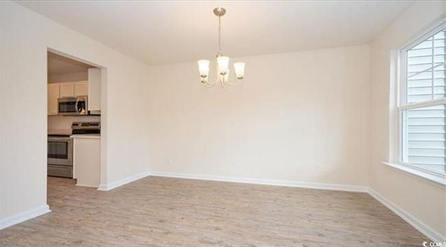 Empty room with baseboards, an inviting chandelier, and light wood-style flooring | Image 5