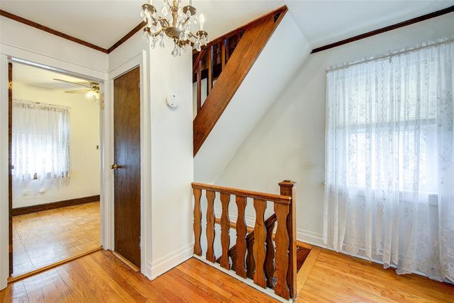 Stairway featuring ornamental molding, wood finished floors, a chandelier, and a ceiling fan | Image 22