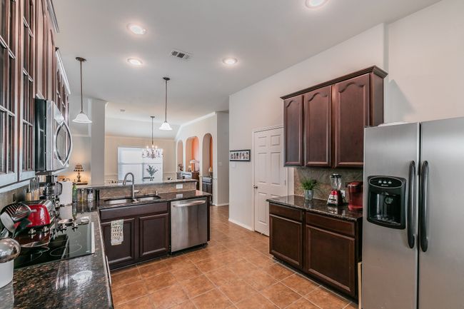 Kitchen featuring a sink, dark brown cabinetry, visible vents, and stainless steel appliances | Image 7