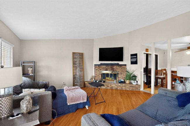Living area featuring ceiling fan, laminate wood finished floors, and a fireplace | Image 4