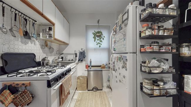 Kitchen featuring white cabinetry, white gas stove, backsplash, and a sink | Image 11