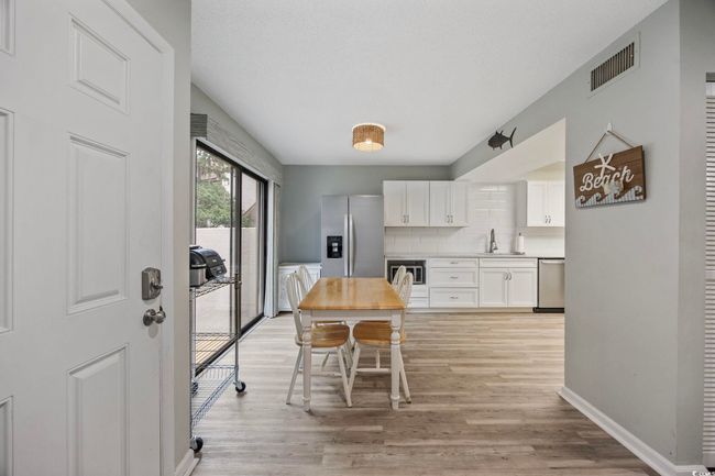 Kitchen featuring appliances with stainless steel finishes, a sink, white cabinetry, light wood finished floors, and decorative backsplash | Image 11