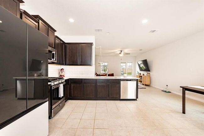 Kitchen with appliances with stainless steel finishes, ceiling fan, recessed lighting, tasteful backsplash, and dark brown cabinetry | Image 16