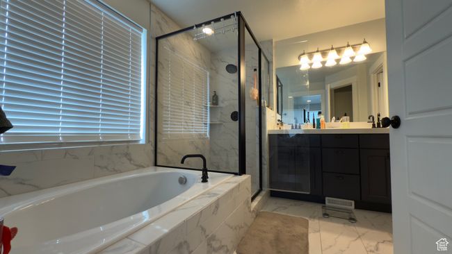 Bathroom featuring a garden tub, marble look tiles, a stall shower, and vanity | Image 14