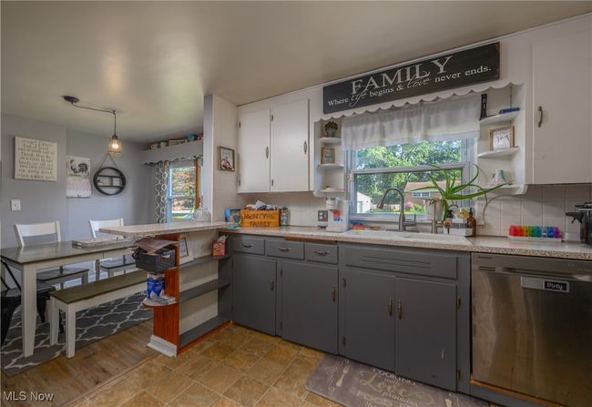 Kitchen with stainless steel dishwasher, open shelves, gray cabinetry, and plenty of natural light | Image 12