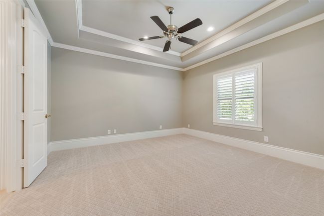 Spare room featuring a tray ceiling, ceiling fan, crown molding, and light carpet | Image 34