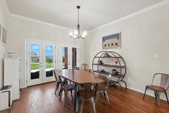 Dining area with french doors, ornamental molding, a chandelier, and wood finished floors | Image 7