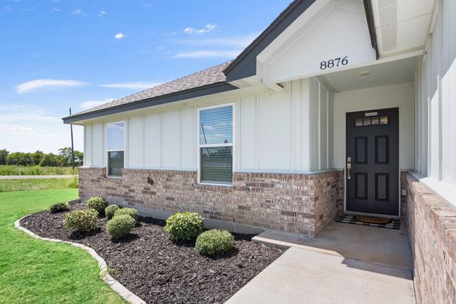 Entrance to property featuring board and batten siding, a shingled roof, brick siding, and a yard | Image 6