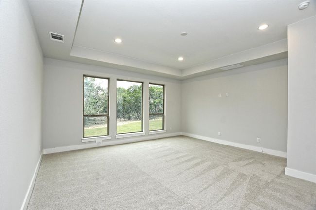 Primary bedroom room featuring a raised ceiling, carpet floors, recessed lighting, and visible vents | Image 16